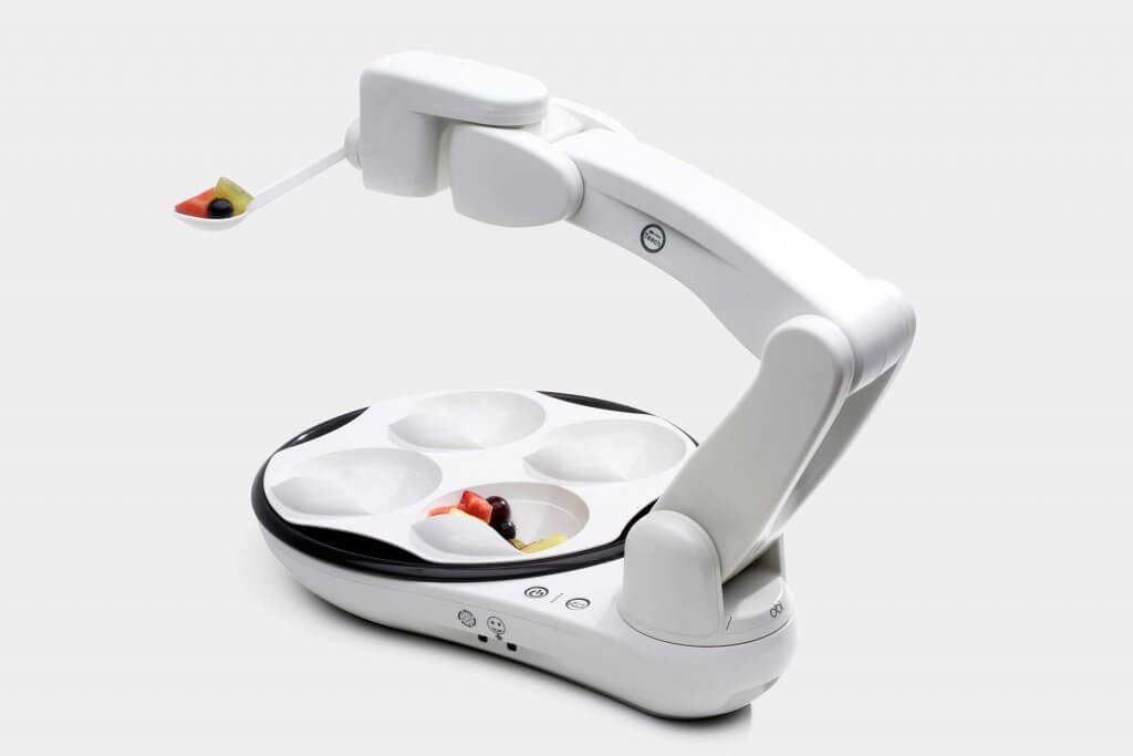 Photo of the Obi adaptive eating robot; #2 on the list of 4 Adaptive Devices for Eating and Drinking. Shown with a spoonful of fresh fruit, Obi is a revolutionary adaptive eating device for individuals with upper extremity strength and mobility limitations.