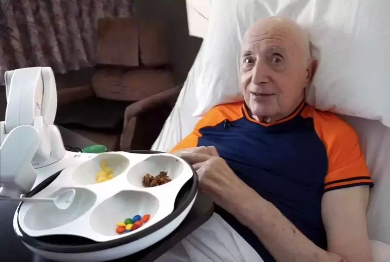 This photo shows a man, Larry, using the Obi assistive eating device